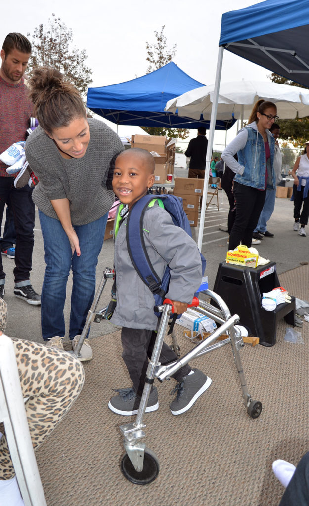 kid-with-walker-being-helped-by-volunteer